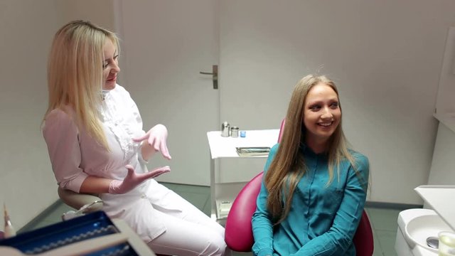 Female dentist talking to a girl in the dental clinic.