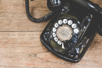 Black antique vintage analog telephone dialing or scrolling phone on wooden table. Contact us...