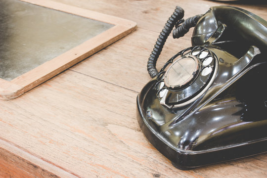 Black antique vintage analog telephone dialing or scrolling phone on old wall with old slate. Contact us concept.