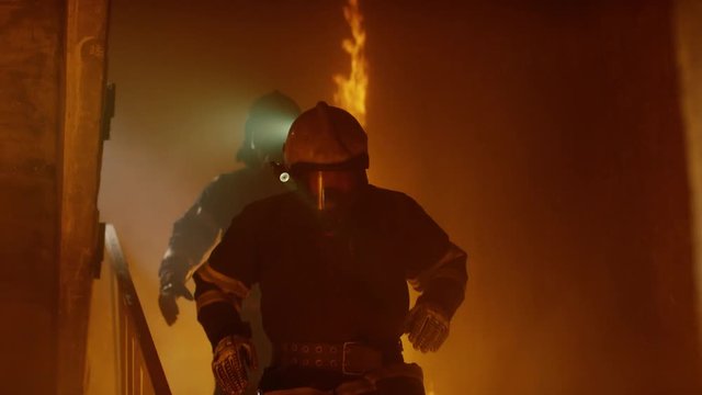 Brave Firefighters Run Down The Burning Stairs. In Slow Motion. Raging Fire is Seen Everywhere.  Shot on RED EPIC (uhd).