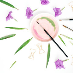 Artist workspace with watercolor, paintbrushes, golden clips, green leaves. Flat lay, top view