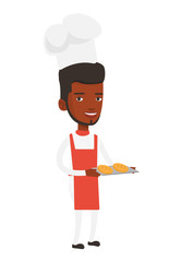 Happy young male baker holding tray of bread.