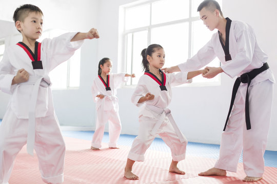 Young instructor teaching children Tae Kwon Do