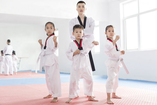 Young instructor teaching children Tae Kwon Do