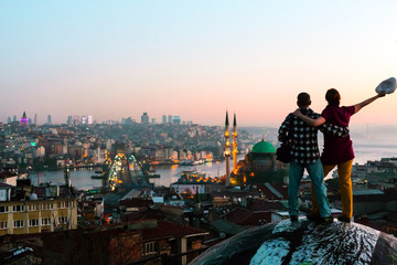 Excited Man and Woman staying rooftop overlooking city at sunrise