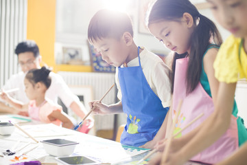 Children painting in the art class with teacher