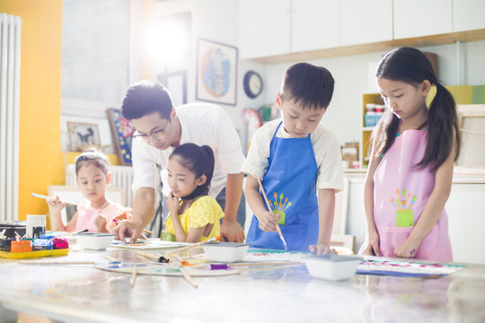 Children painting in the art class with teacher