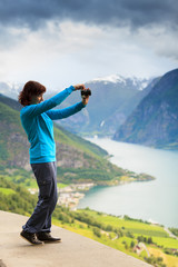 Female tourist taking photo at norwegian fjord
