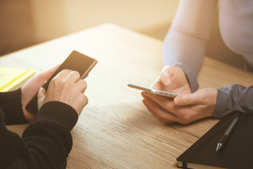 Two businesswomen using smartphones on business meeting