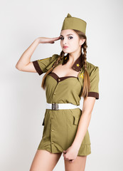 sexy fashionable woman in military uniform and forage-cap, put a hand to her head, salutes