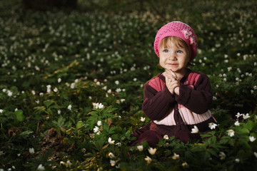 beautiful little girl in forest on flowers field