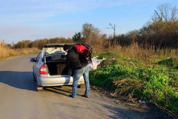 The guy puts corpse of the girl in the trunk of a car