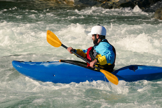 Side Profile of Extreme Kayaker Paddling in Raging River of White Water Rapids