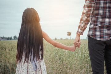 A girl holding hands with father