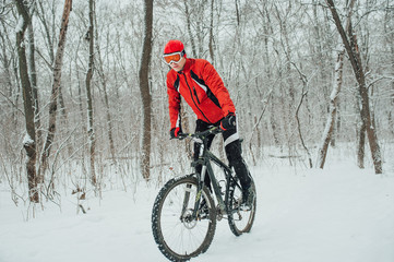 Extreme cyclist rides in the winter snowy forest