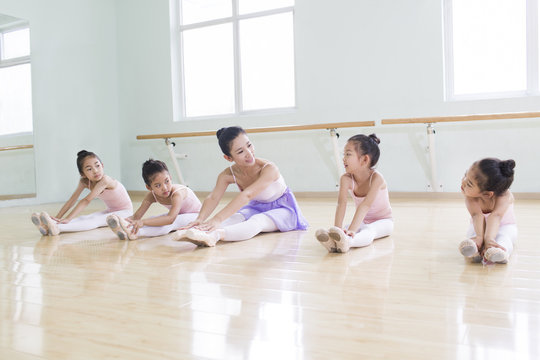 Young ballet instructor teaching girls in ballet studio
