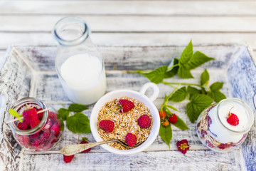Musli and yogurt with fresh raspberry fruit on wooden tray. 
