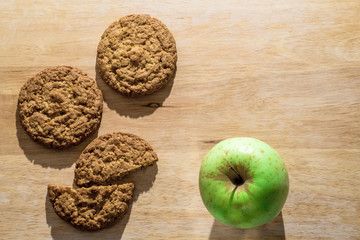Oatmeal cookies on a wooden board with green apple