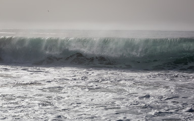 Ocean waves on beach in Nazare. Autumn day on the Atlantic coast in Portugal.