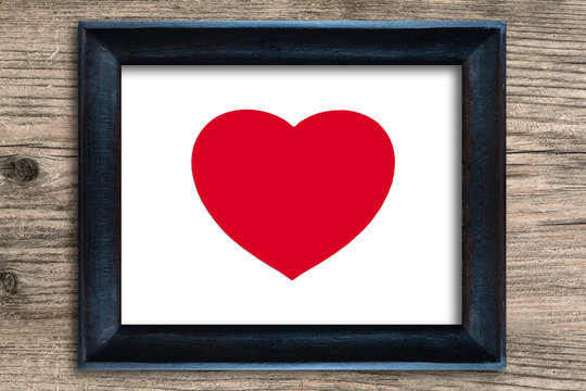 Red heart in photo frame on wooden background , valentine concep