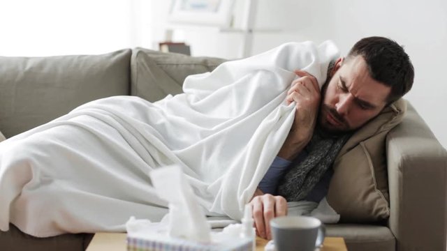 ill man with thermometer having flu at home
