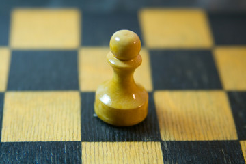 The one pawn on the chessboard with black and yellow squares it's like a man on the battlefield