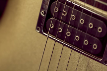 Soft image of a black humbucking pickup on a gold guitar. Rock, Blues or Jazz club music poster image with copy space