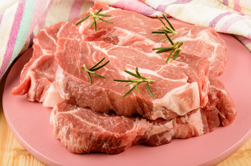 pork shoulder with rosemary on a pink wooden board