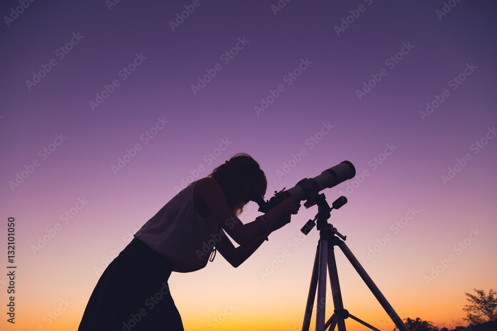 Wall mural girl looking at the stars with telescope beside her.