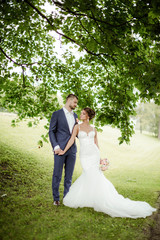 Young wedding couple enjoying romantic moments outside on a summer meadow