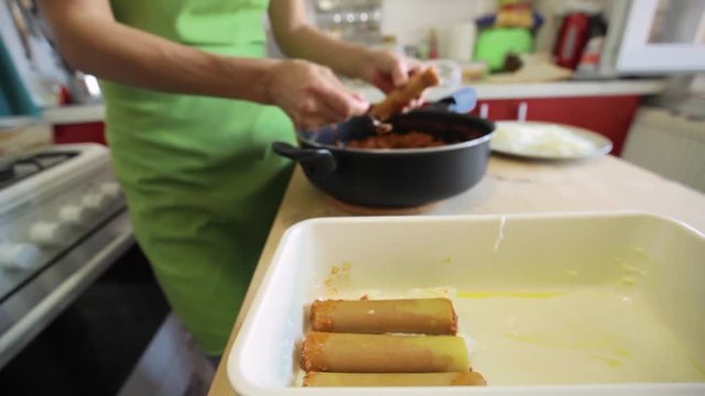 Woman cook making cannelloni, a lasagna variety