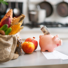 Closeup on money in piggy bank and purchases from local market o