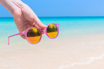 Fototapeta na wymiar Woman hand hold sunglasses over sea background
