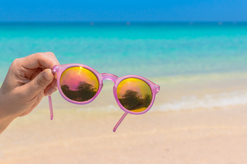 Woman hand hold sunglasses over sea background