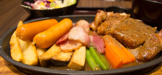 Grilled steaks with sausages vegetables in a pan grill on the ta