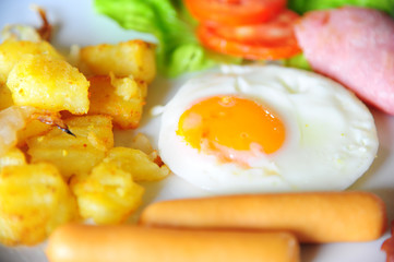 Close up of Breakfast with fried egg, sausage, ham and grill pat