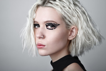 Studio beauty portrait of young woman with black graphic makeup.
