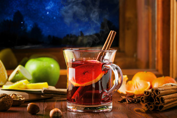 Traditional winter holiday alcoholic drink. Mulled wine with lemon slice on a table. Starry night...