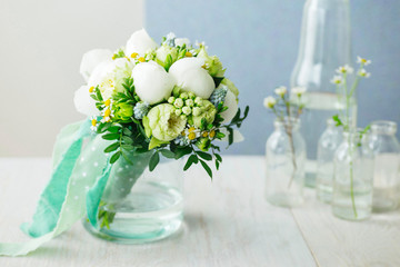 Fresh, spring wedding bouquet made with peonies in rustic glass jar. Pastel color palette.