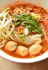 large noodle with pork ball in tom yum spicy soup topping raw bean sprout on bowl