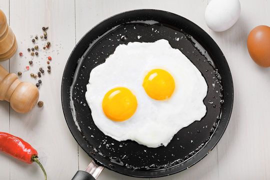 Two fried eggs in a frying pan cooked for breakfast. Delicious international meal on a table. Homemade food, top view.
