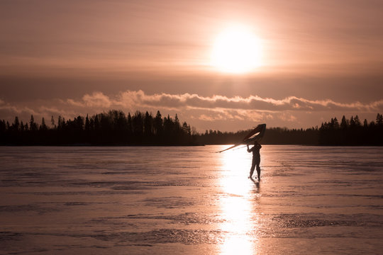 Kitewing skier at a frozen lake during sunset
