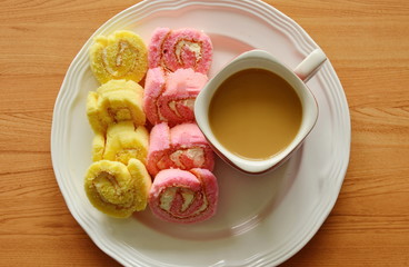 mini strawberry and vanilla jam roll with coffee on dish