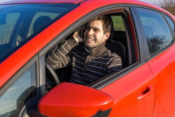 Man is driving a car, holds telephone and calling with someone.