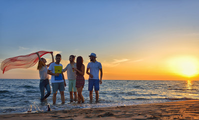 Fototapeta premium group of happy young people dancing at the beach on beautiful summer sunset
