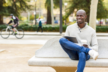 Fototapeta premium Black young man with tablet computer and take away coffee