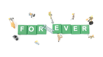 Miniature worker team building word forever on white background