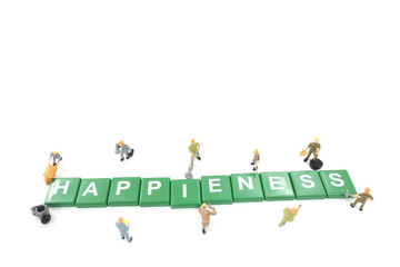 Miniature worker team building word Happiness on white background