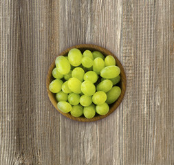 Grapes in a wooden bowl. Green grapes Kish Mish on a wooden background. Top view.