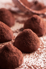Fototapeta na wymiar Chocolate truffles with sweet cream inside on the wooden background